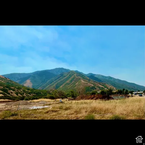 Expansive natural landscape featuring rolling hills and distant mountains under a clear sky