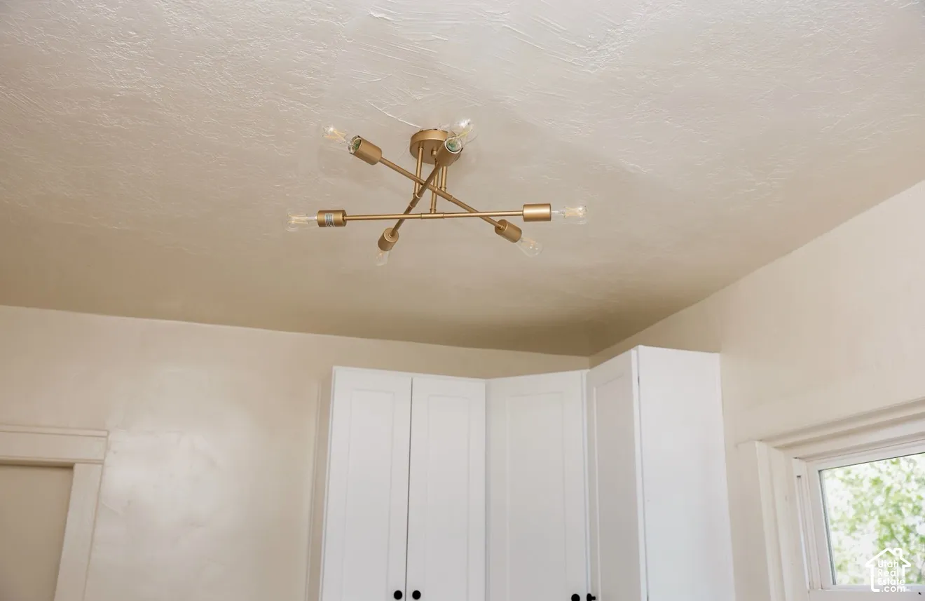 Modern gold-finish semi-flush mount ceiling fixture with exposed bulbs, white cabinetry, and a window with natural light