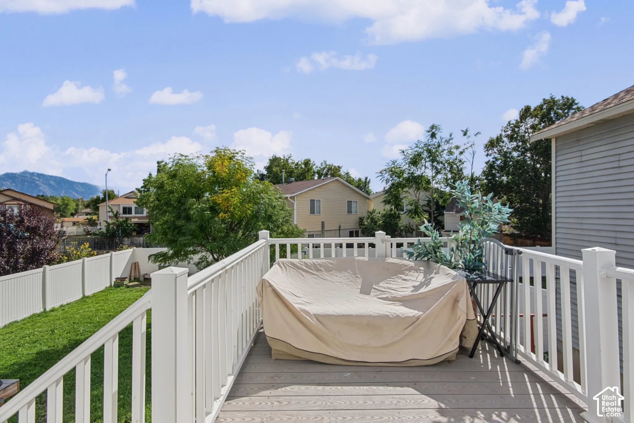 Expansive outdoor deck with white railing, composite decking, and distant mountain scenery