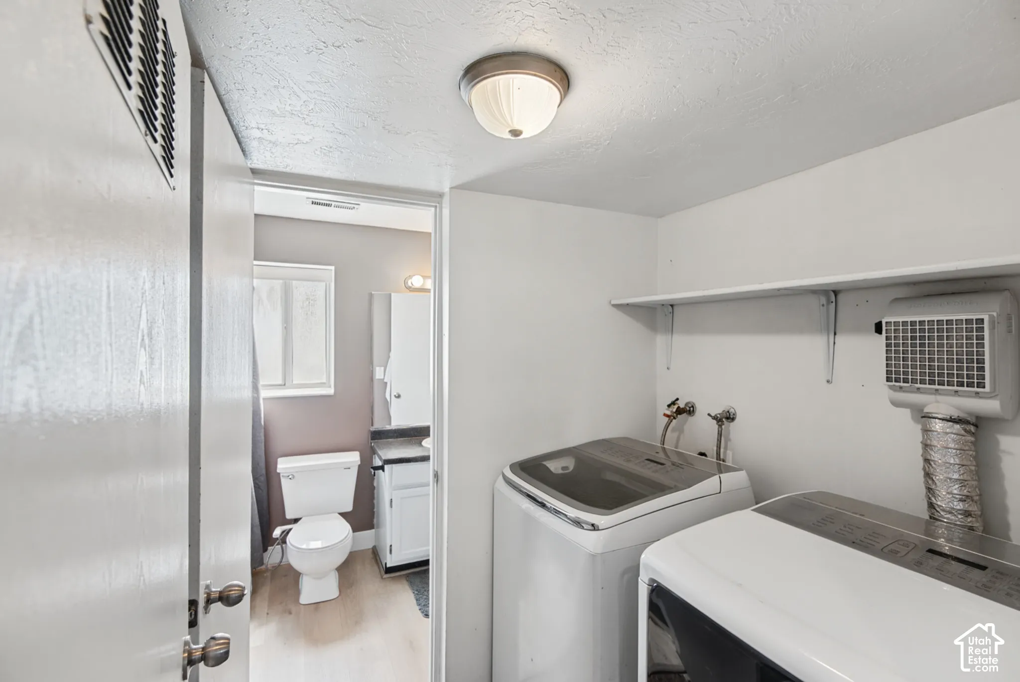 Dedicated laundry area with wall-mounted shelving and ceiling-mounted light fixture