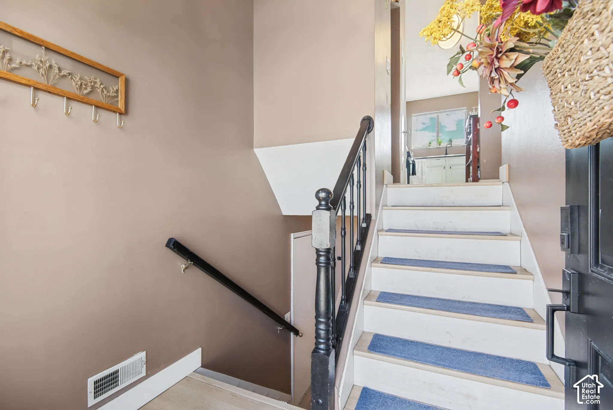 Staircase featuring dark wood handrails and balusters, white risers, and light-toned treads