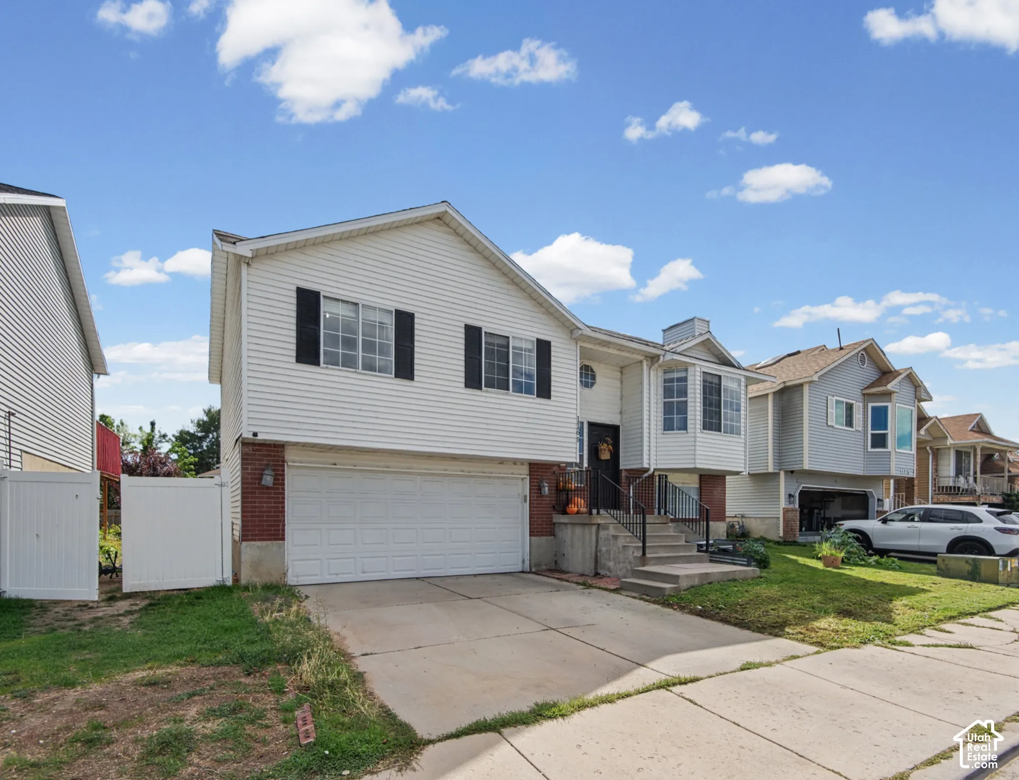 Front exterior with white siding, brick accents, and attached two-car garage