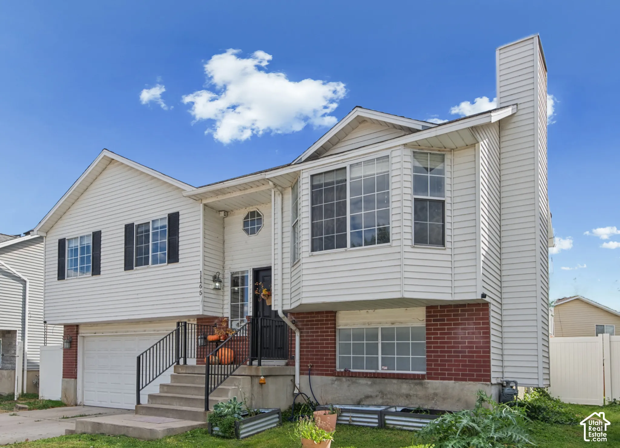 Split-level residence featuring white siding and red brick accents