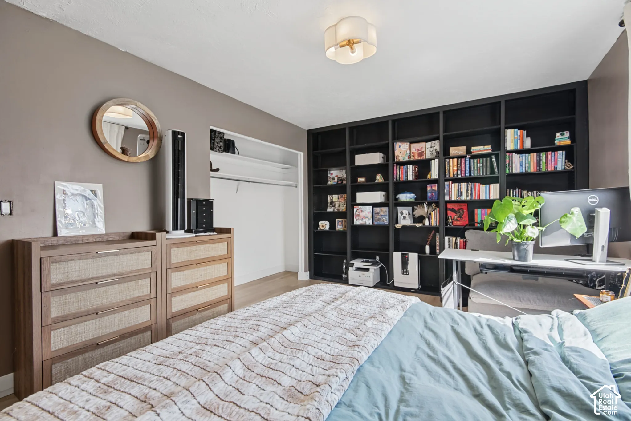 Built-in shelving, flush-mount ceiling light, light wood-finish flooring, and open closet with shelving