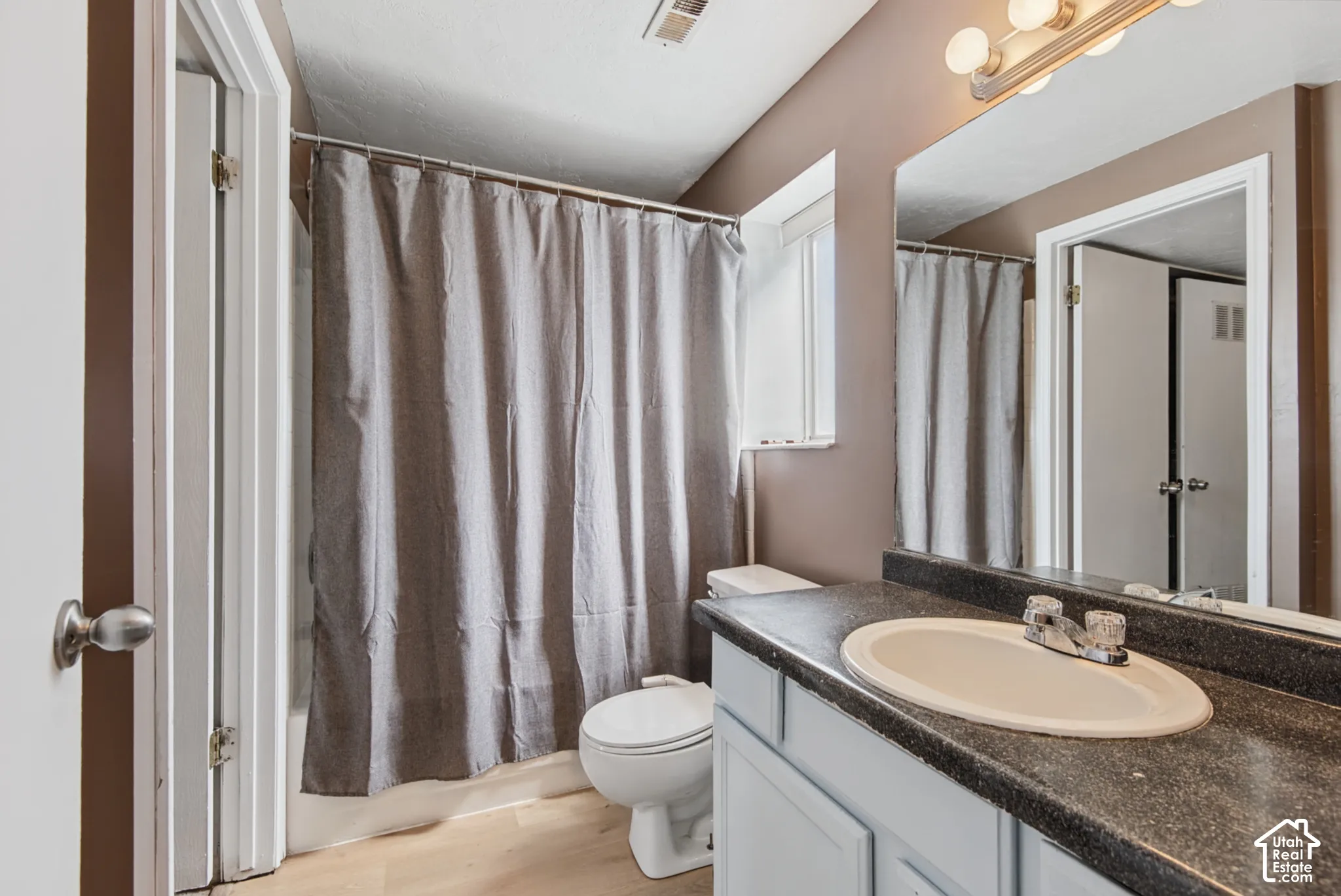Single vanity with an oval sink, dark countertop, and light-colored cabinetry