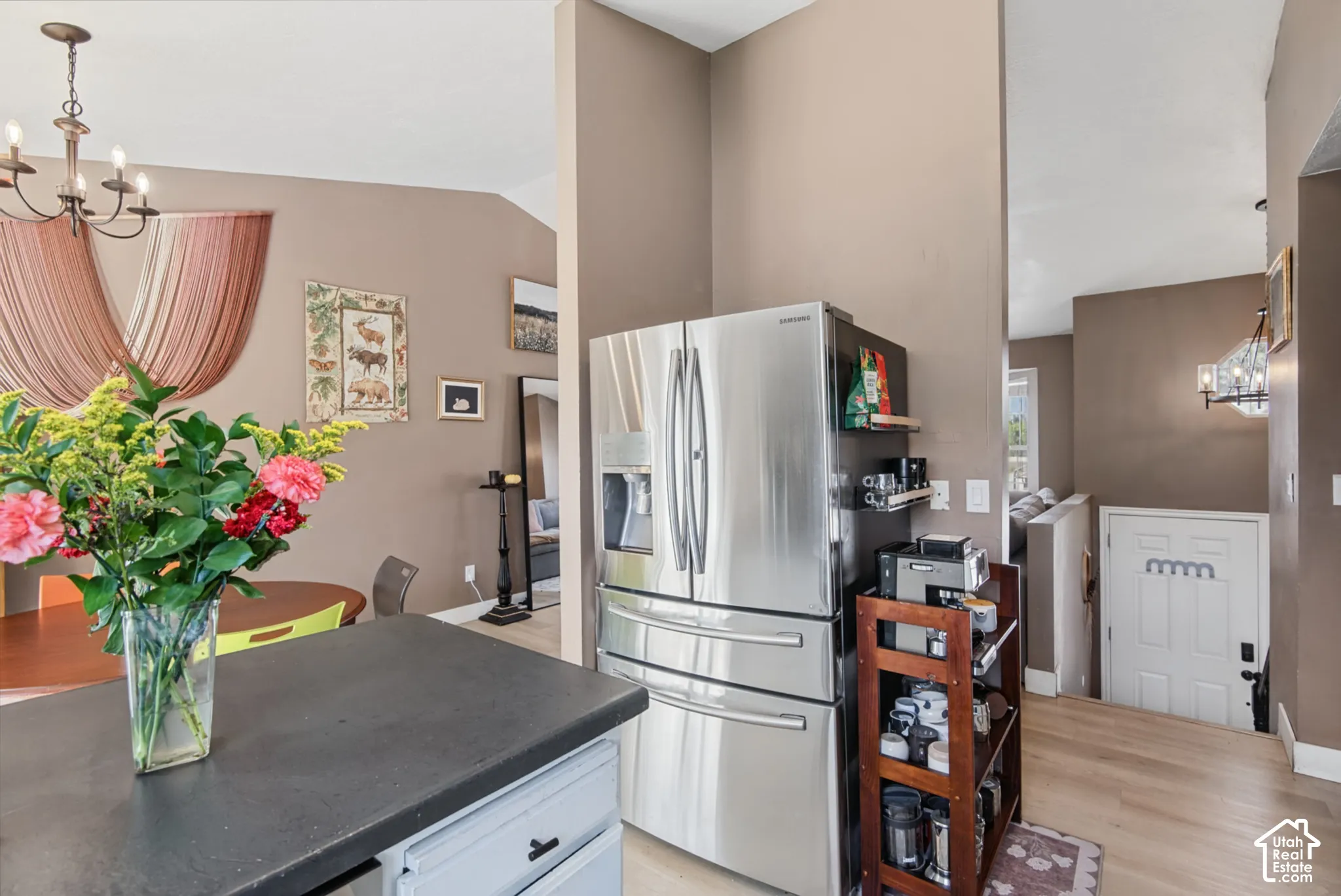 Stainless steel refrigerator, light wood-finish flooring, a wall-mounted light fixture, and a white paneled door