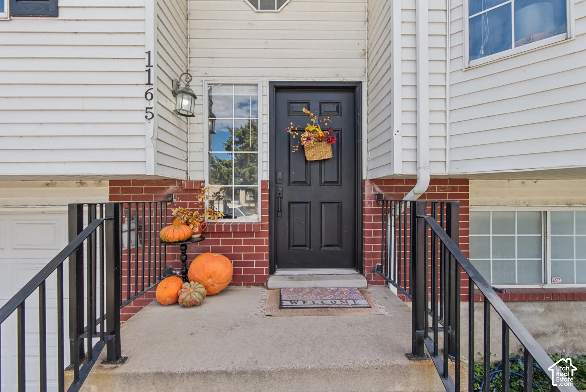 Front entry with a dark paneled door, exterior wall lantern, and brick detailing
