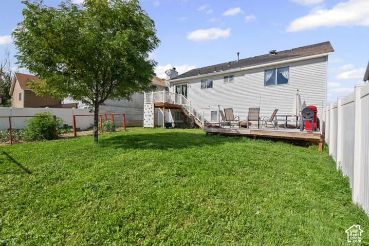 Expansive backyard featuring a mature tree, privacy fencing, and a multi-level wood deck with white railings