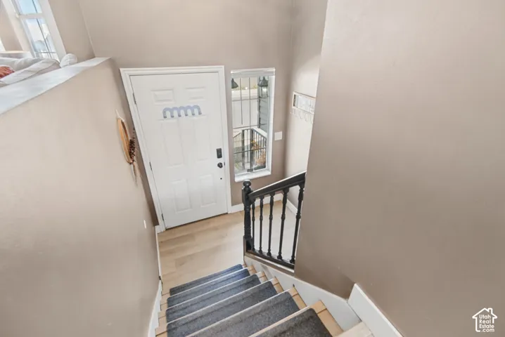 White paneled entry door with dark hardware, light wood-finish flooring, and a window with security bars