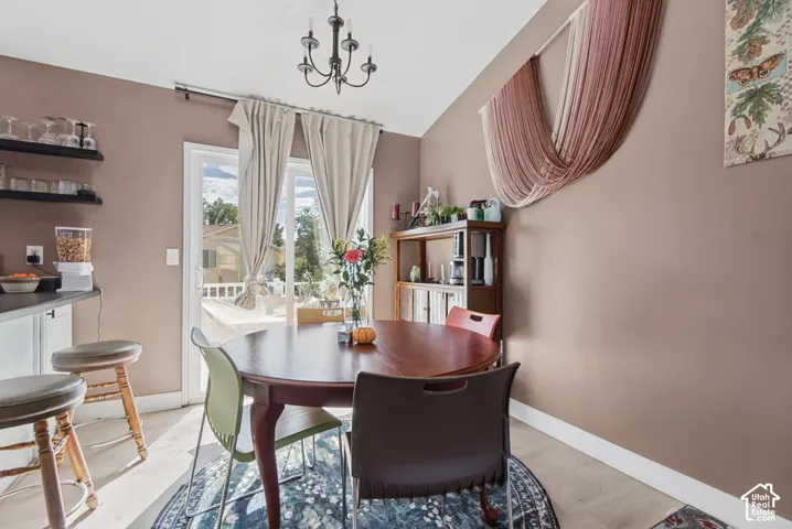 Recessed lighting and a chandelier illuminate the dining area, featuring an adjacent kitchen counter with open shelving