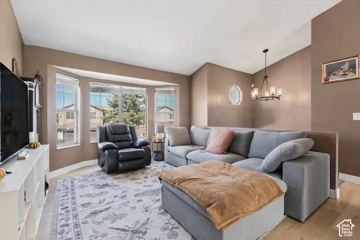 Bay window with multiple panels, wood-finish flooring, and a multi-arm chandelier