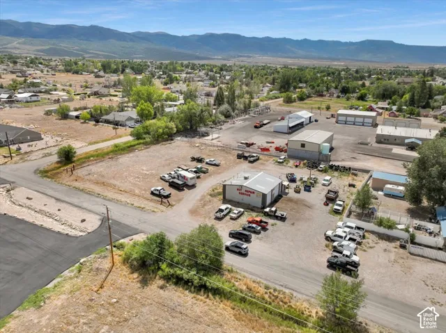 Multiple commercial buildings with a large gravel lot, surrounded by open land and distant mountains