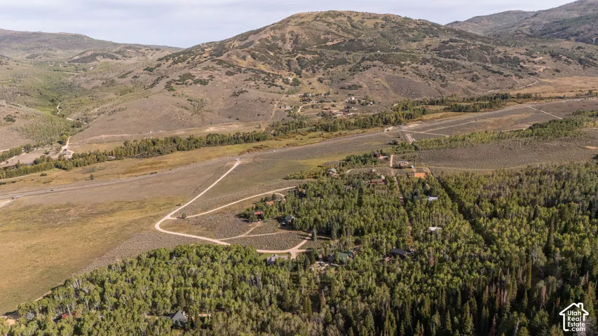 Expansive mountain terrain featuring scattered residences, vast undeveloped land, and winding unpaved roads