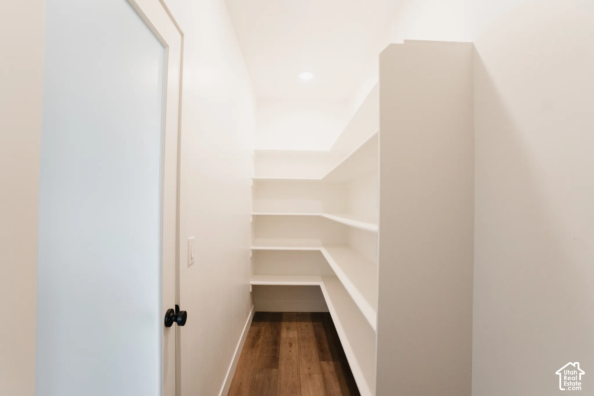 Built-in shelving, wood-finish flooring, recessed lighting, white walls