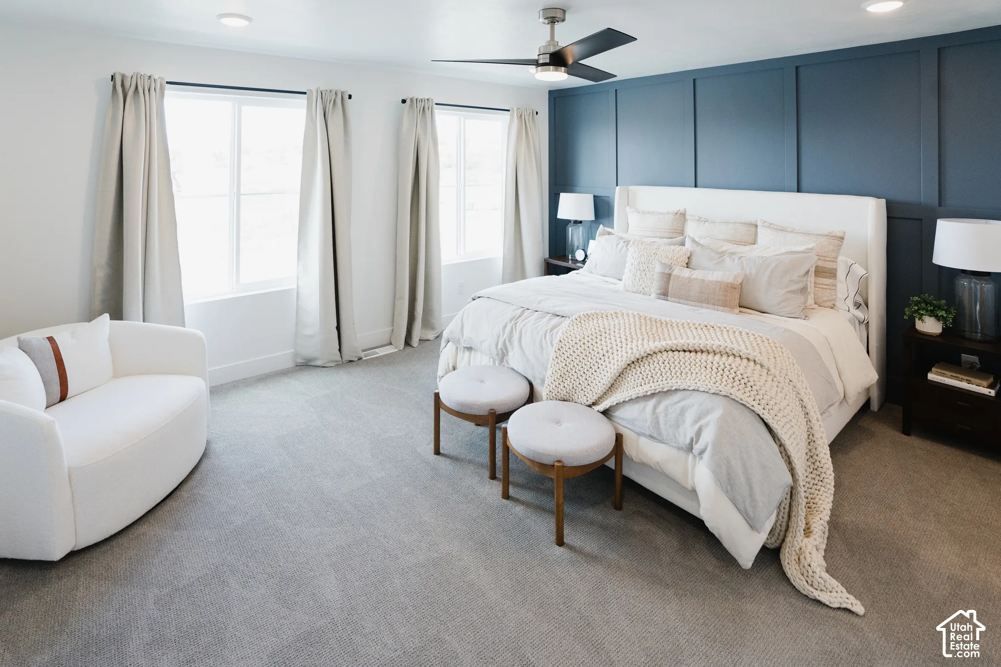 Recessed lighting, ceiling fan, accent wall with vertical paneling, light gray carpeting, and multiple windows