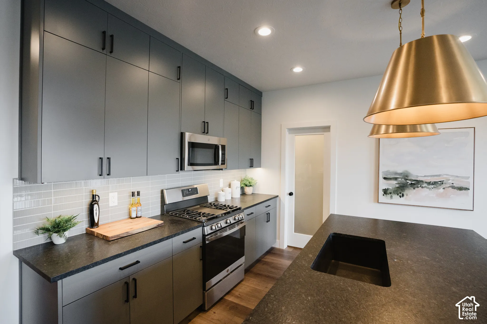 Kitchen featuring dark gray cabinetry, stainless steel appliances, dark stone countertops, and a white subway tile backsplash
