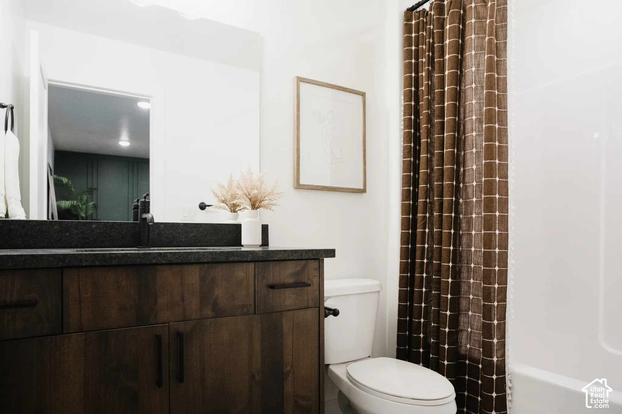 Dark wood-finish vanity with black hardware and a dark countertop
