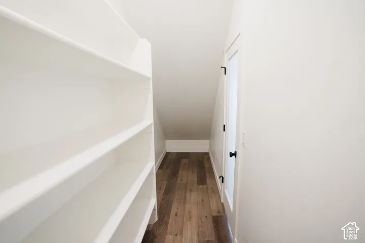 Built-in shelving with multiple levels, wood-finish flooring, white walls, and a white door with dark hardware