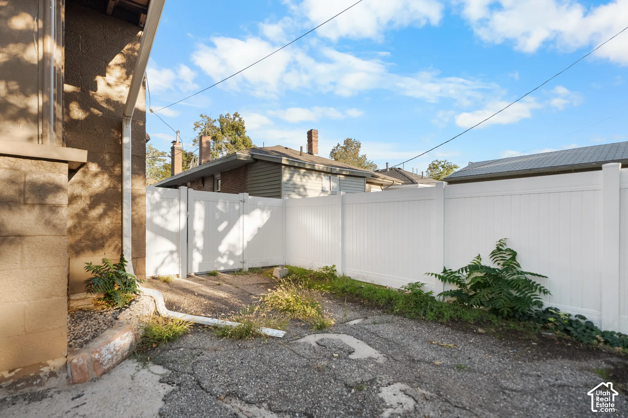 White privacy fencing, vinyl fence gate, and a concrete paver driveway