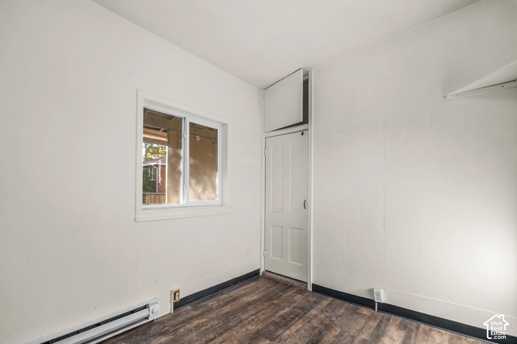 Wood-finish flooring with white walls and a white-framed window