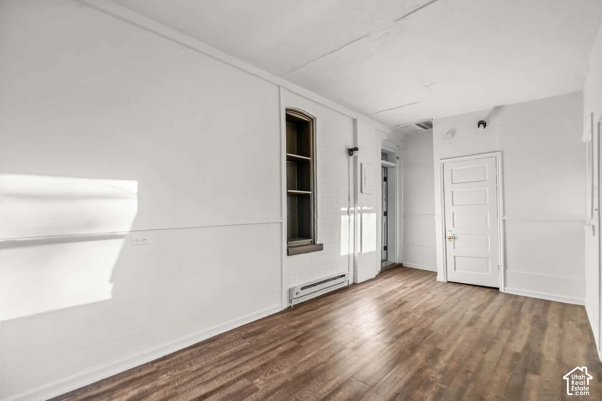 Wood-finish flooring, white walls, and a multi-pane window