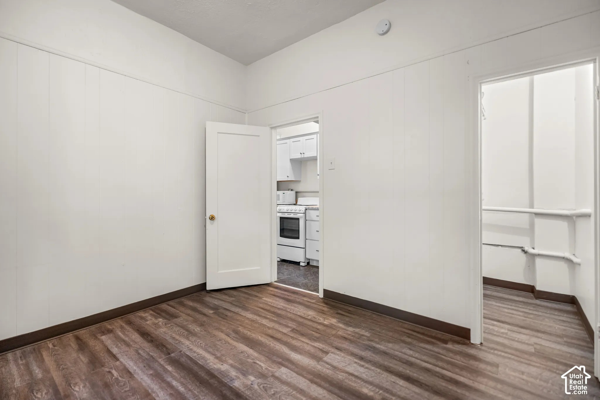 Wood-finish flooring with white paneled walls and a white ceiling