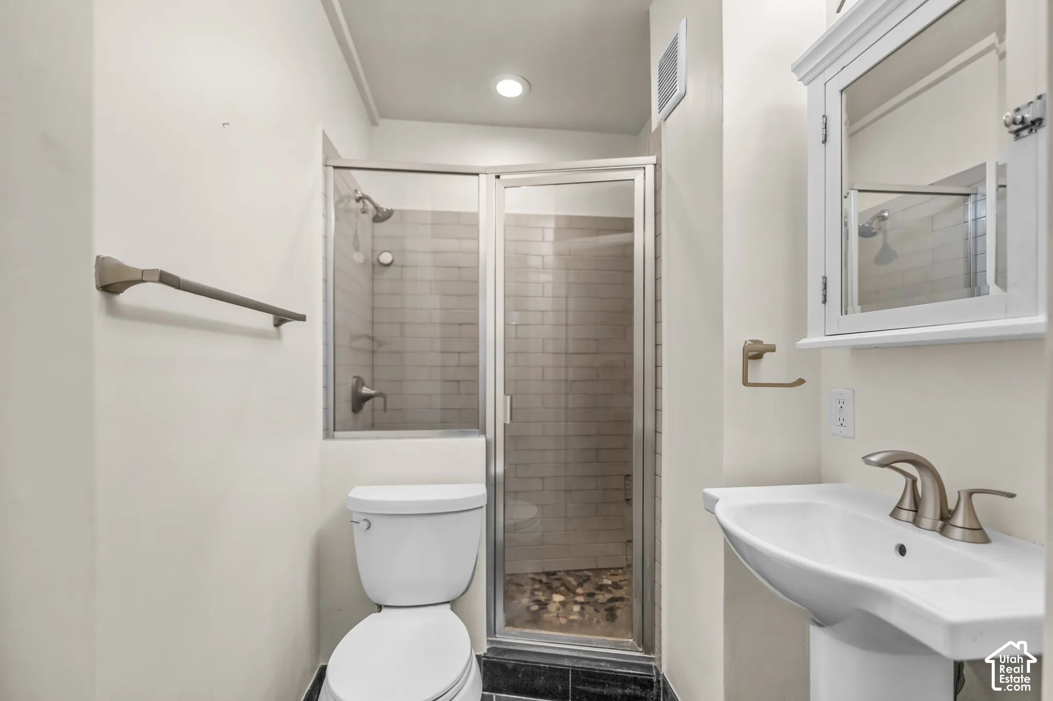 Pedestal sink with brushed nickel faucet, shower enclosure with glass door, subway tile shower surround, recessed lighting, and wall-mounted medicine cabinet
