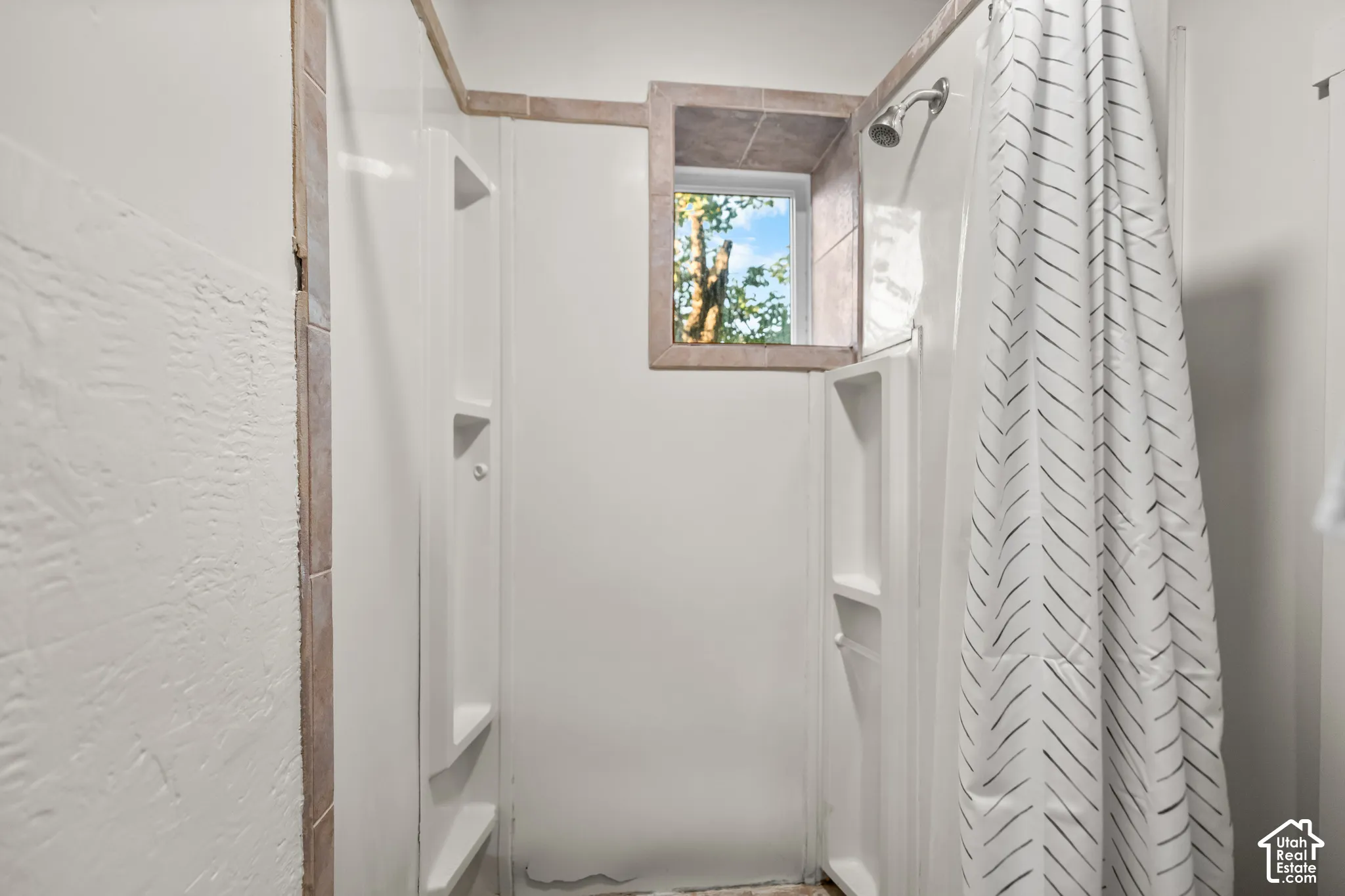 Shower enclosure with integrated shelving, tiled window surround, and shower head