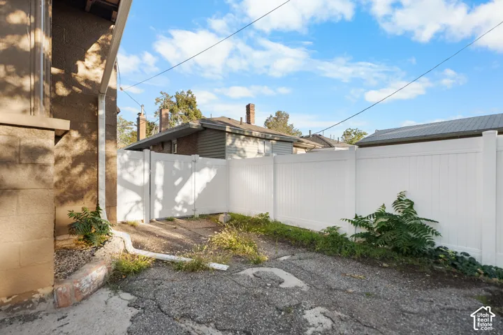 White privacy fencing, vinyl fence gate, and a concrete paver driveway