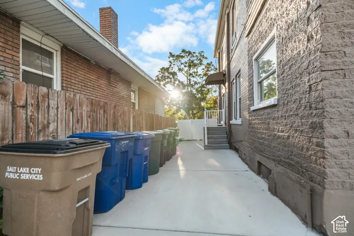 Brick exterior, wood fence, concrete pathway, exterior staircase, white railing