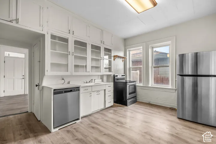 Kitchen featuring wood-finish flooring, white cabinetry, a stainless steel refrigerator, a black range, and a stainless steel dishwasher