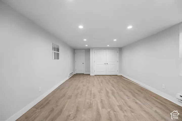 Recessed lighting, wood-finish flooring, white walls, white trim, and white double doors