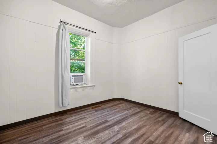 Wood-finish flooring with white paneled walls and a white interior door
