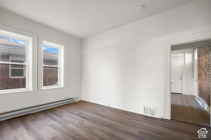Wood-finish flooring, white paneled wainscoting, and two large windows