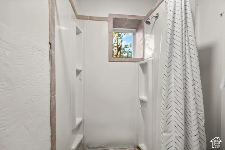 Shower enclosure with integrated shelving, tiled window surround, and shower head