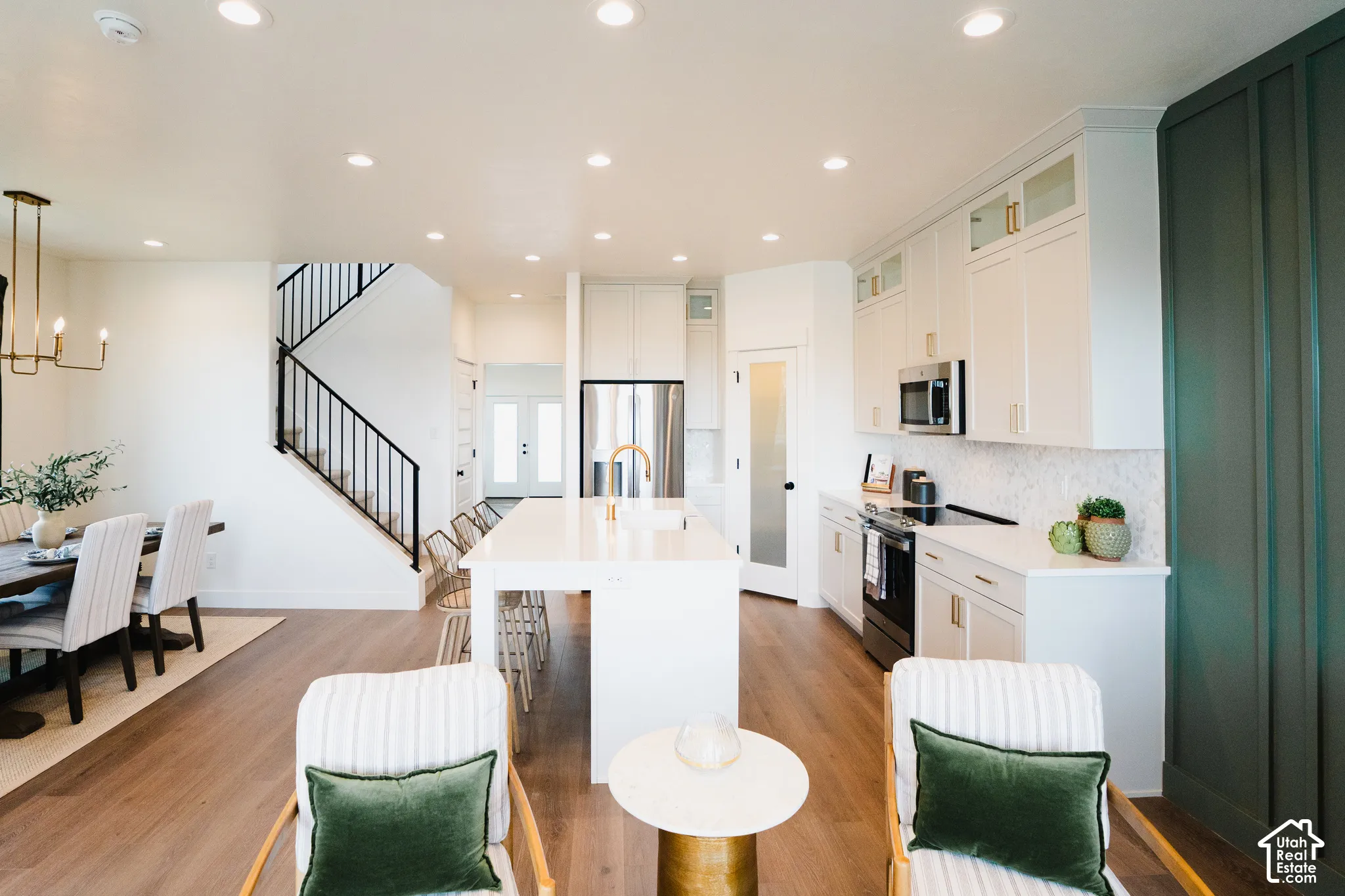 Open-concept kitchen with a white island, white cabinetry, and stainless steel appliances