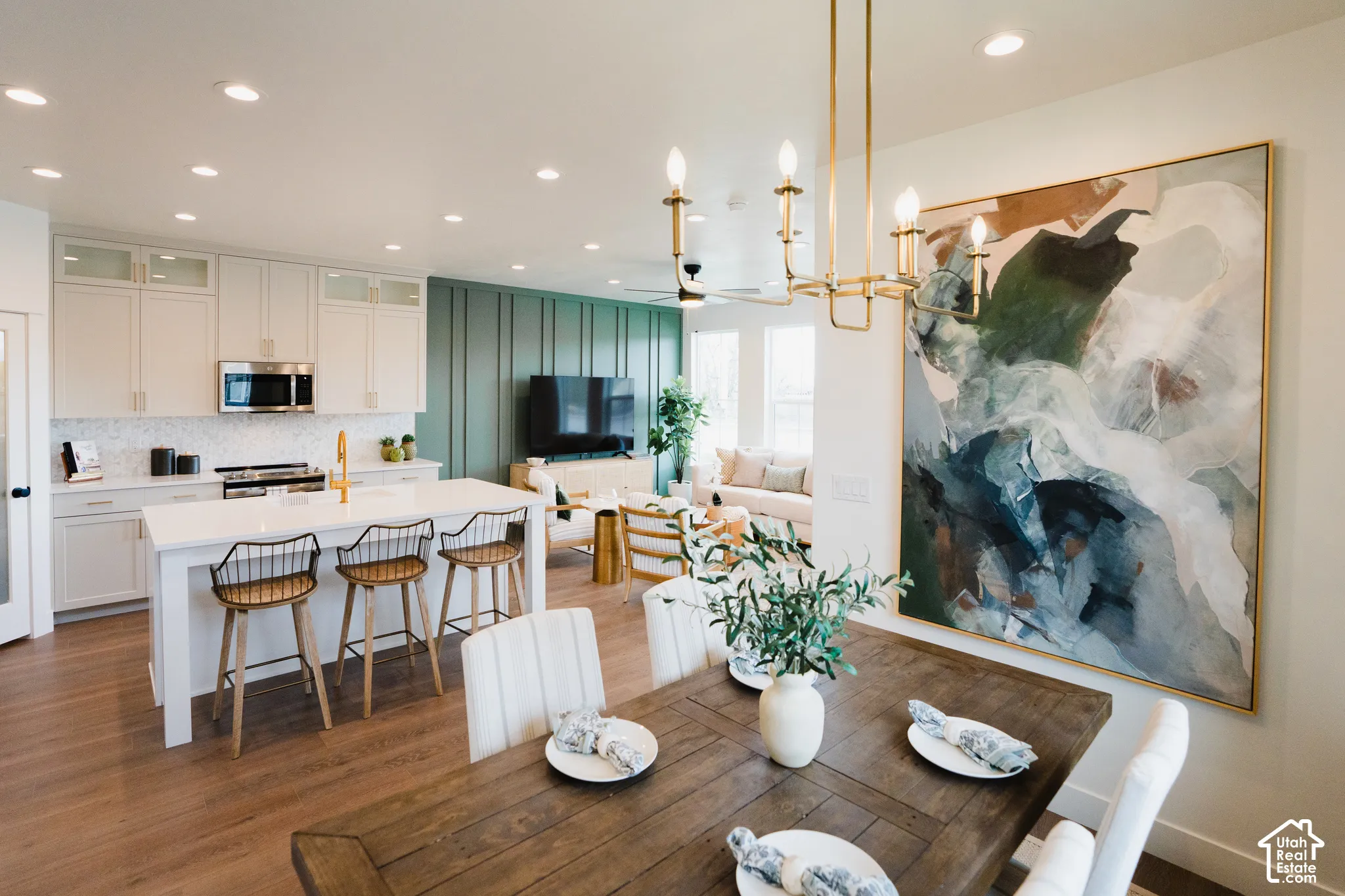 Open-concept living space with wood-finish flooring, a kitchen island with seating, stainless steel appliances, and recessed lighting