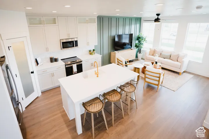 Kitchen featuring white cabinetry with gold-finish hardware, stainless steel appliances, and a central island