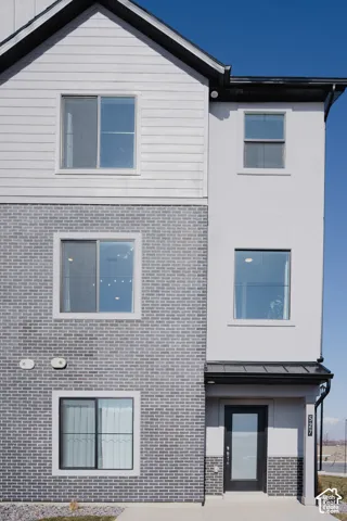 Multi-level exterior featuring light gray brick, horizontal siding, and stucco finishes