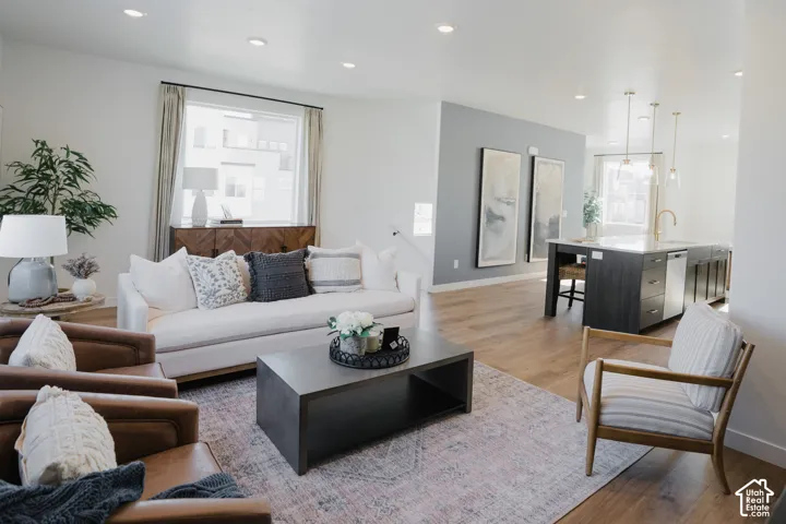 Bright living area with recessed lighting, wood-finish flooring, and a large window