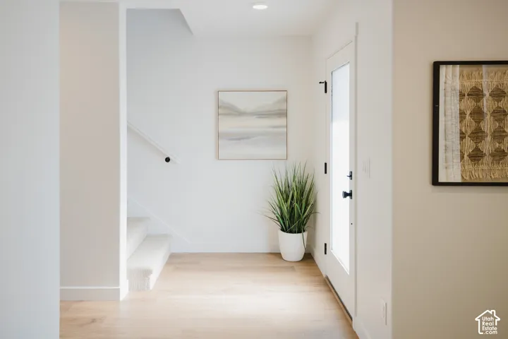 Wood-finish flooring with a white door featuring matte black hardware