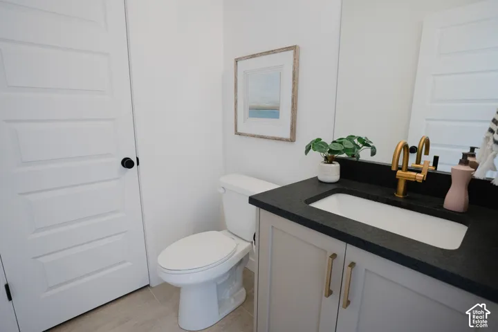 Vanity with a dark countertop, white integrated sink, and brass-finish faucet