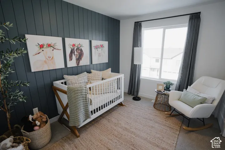 Accent wall with vertical paneling, large window with drapes, and neutral wall paint