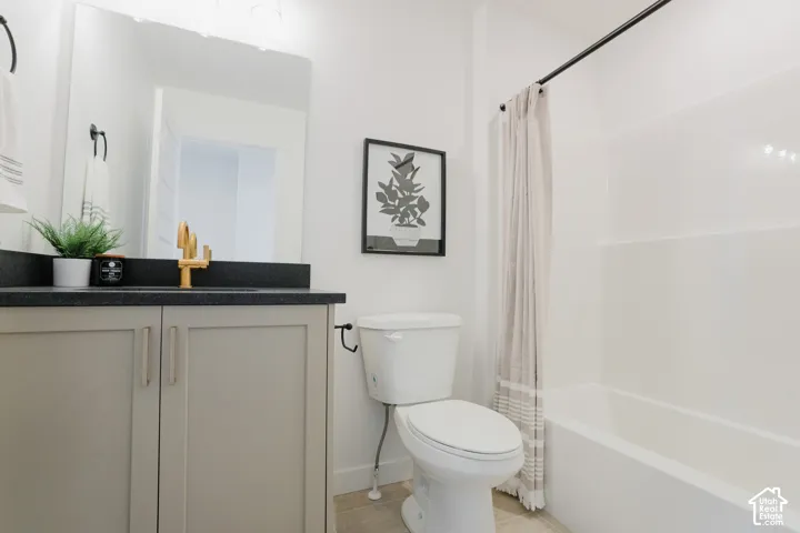 Bathroom with a single vanity, dark countertop, gold-tone faucet, and an integrated tub/shower unit