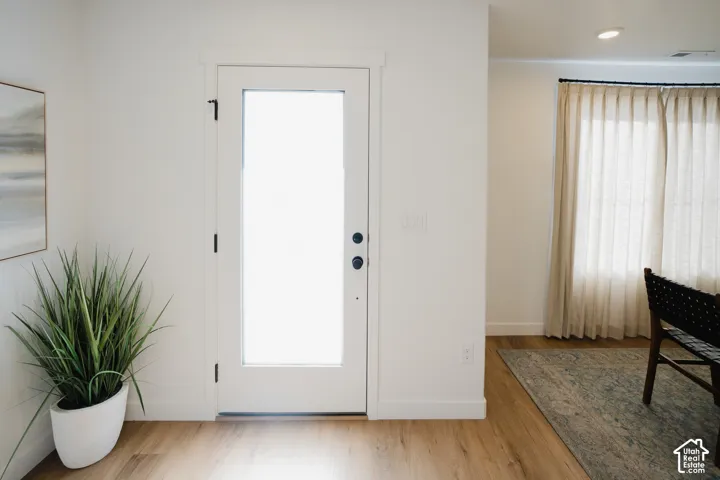 Full-light door with matte black hardware, recessed lighting, and wood-finish flooring
