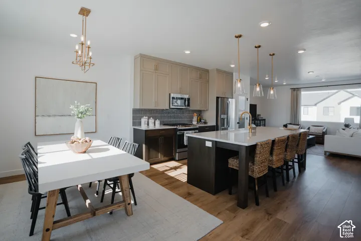 Open-concept floor plan featuring wood-finish flooring, a kitchen island with seating, pendant lighting, and recessed lighting