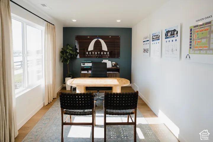 Recessed lighting, wood-finish flooring, a large window, a dark accent wall, and white wall finishes