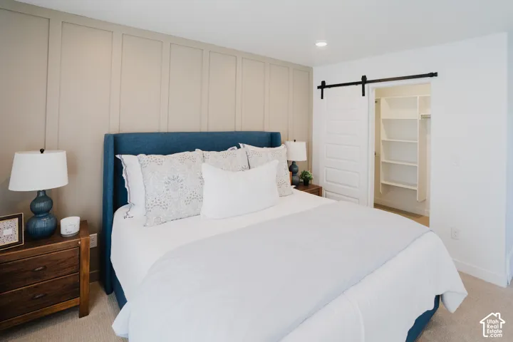 Accent wall with vertical paneling, recessed lighting, white barn door, and built-in closet shelving