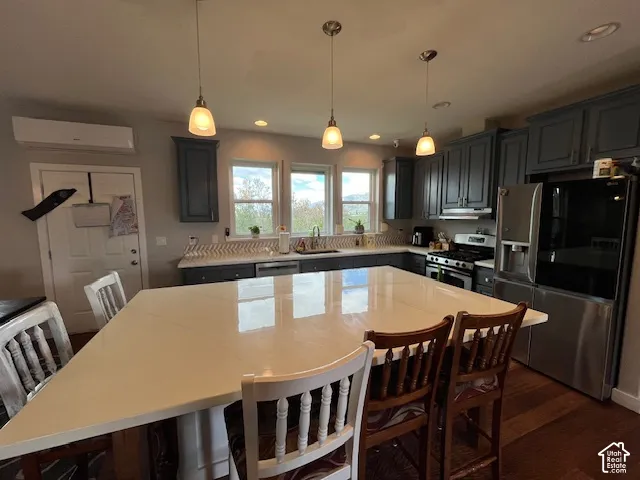 Kitchen featuring a large island, gray cabinetry, stainless steel appliances, and a tile backsplash