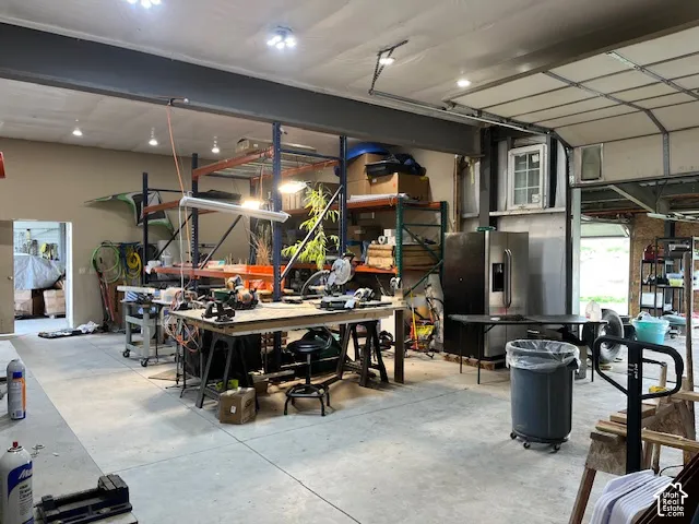 Concrete flooring, exposed ceiling beams, recessed lighting, and a roll-up door